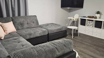 A modern living room with a sectional sofa, a flat-screen TV, and a white entertainment unit.
