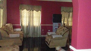A living room with two armchairs, a television, and a cabinet. - Large home for retreat and family vacation (Mandeville)