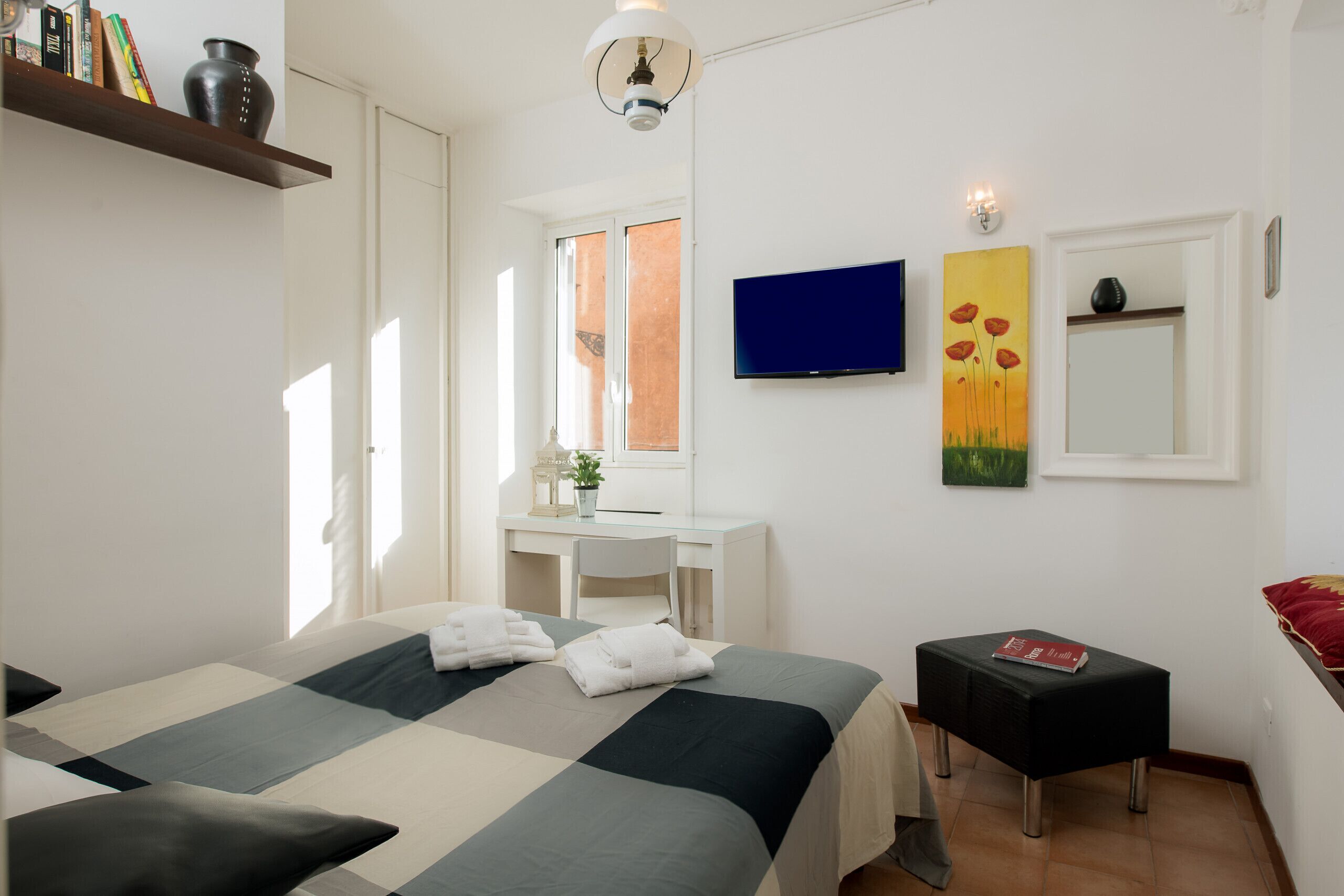 Une chambre d’hôtel avec un lit, un bureau, une chaise, une télévision, un tableau et une petite table.