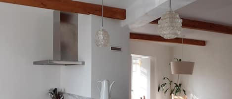 Cocina moderna con encimera de mármol, pileta de acero inoxidable y vigas de madera.