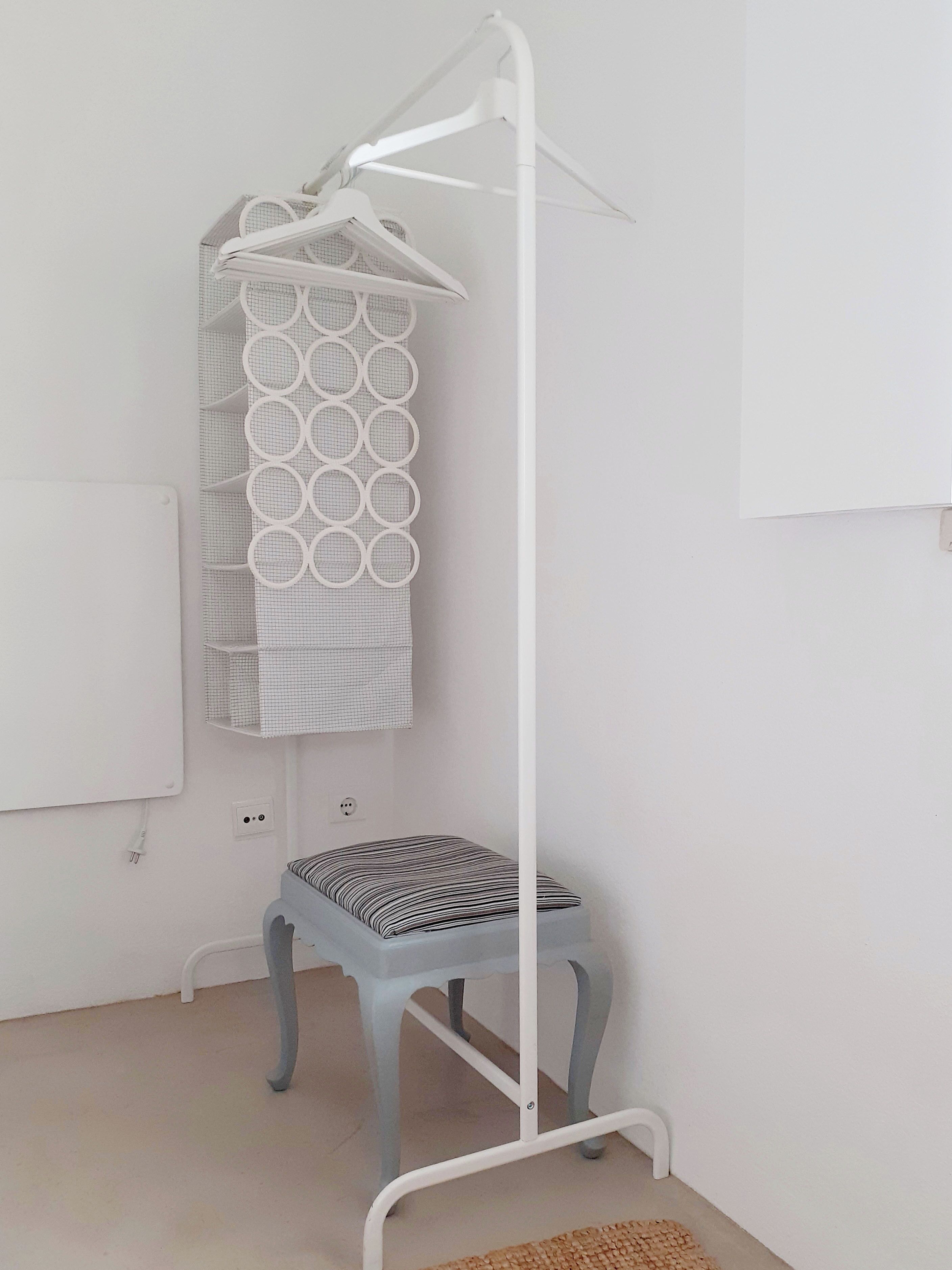 Een witte kamer met een grijze stoel, een witte radiator en een witte muur.