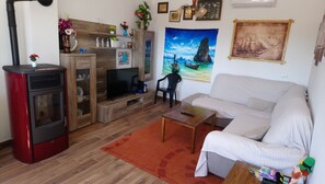 A living room with a sofa, a television, a red heater, and a wooden cabinet.