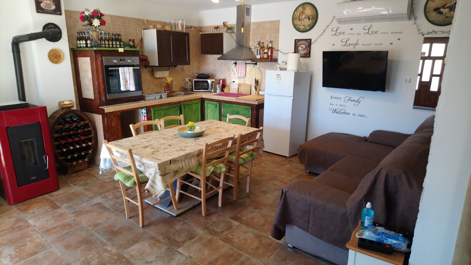 Een kleine keuken met een eettafel, stoelen, een koelkast en een televisie.