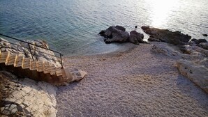 A coastal area with a staircase leading down to a pebble beach, surrounded by rocky formations. - CASA BOZZERO, elegant and modern rustic with 2 apartments (Krnica)