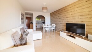 A modern living room with a white sofa, a flat-screen TV, and a wooden accent wall. - Spacious and cozy apartment  (Palm-Mar)