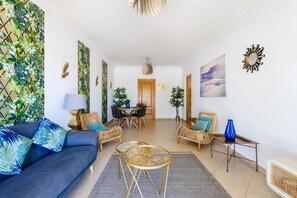 A living room with a sofa, two chairs, a coffee table, and a dining area with a table and chairs.