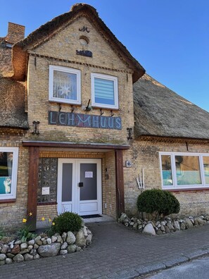 A building with a sign reading 'LEHMHUS' and a traditional thatched roof.
