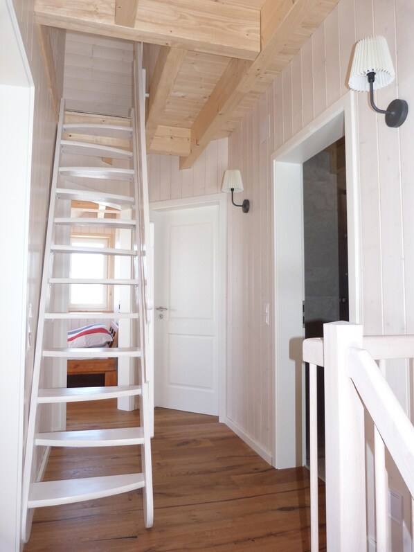 Un escalier en bois mène à une chambre à coucher qui contient un lit et une table de chevet.