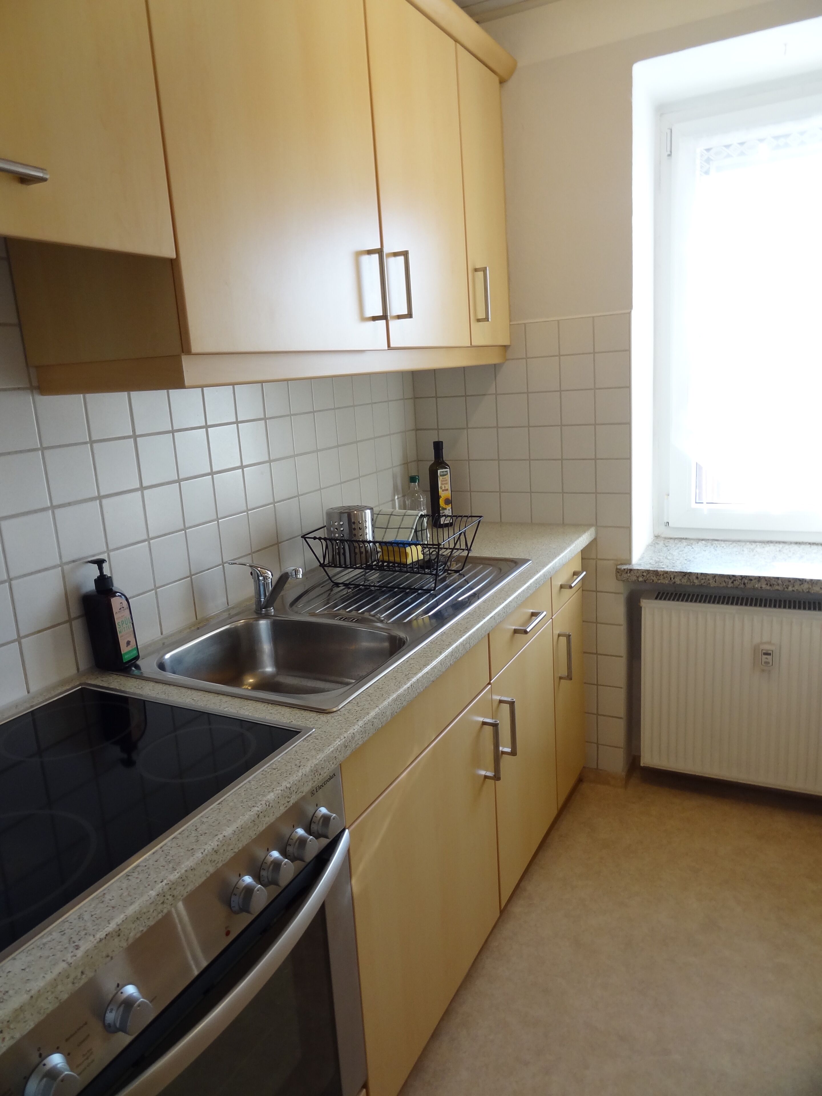 A kitchen with a stove, sink, and cabinets.