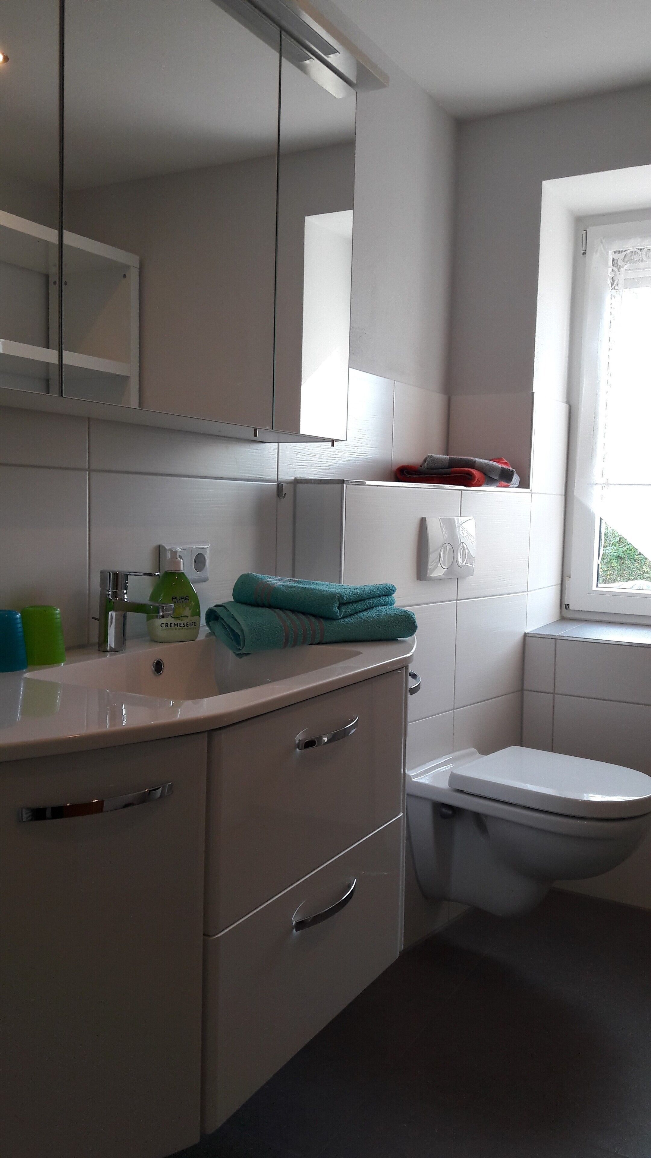 A modern bathroom with a sink, mirror, and toilet.