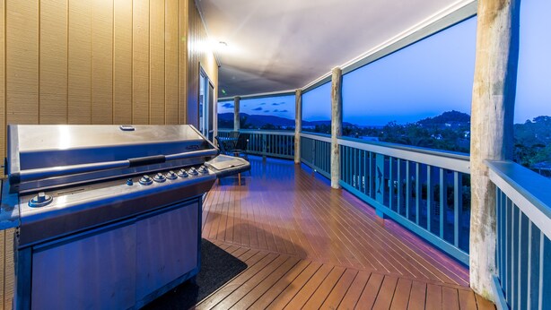 Ein überdachter Außenbereich mit Grill, Holzdeck und Blick auf die Landschaft.