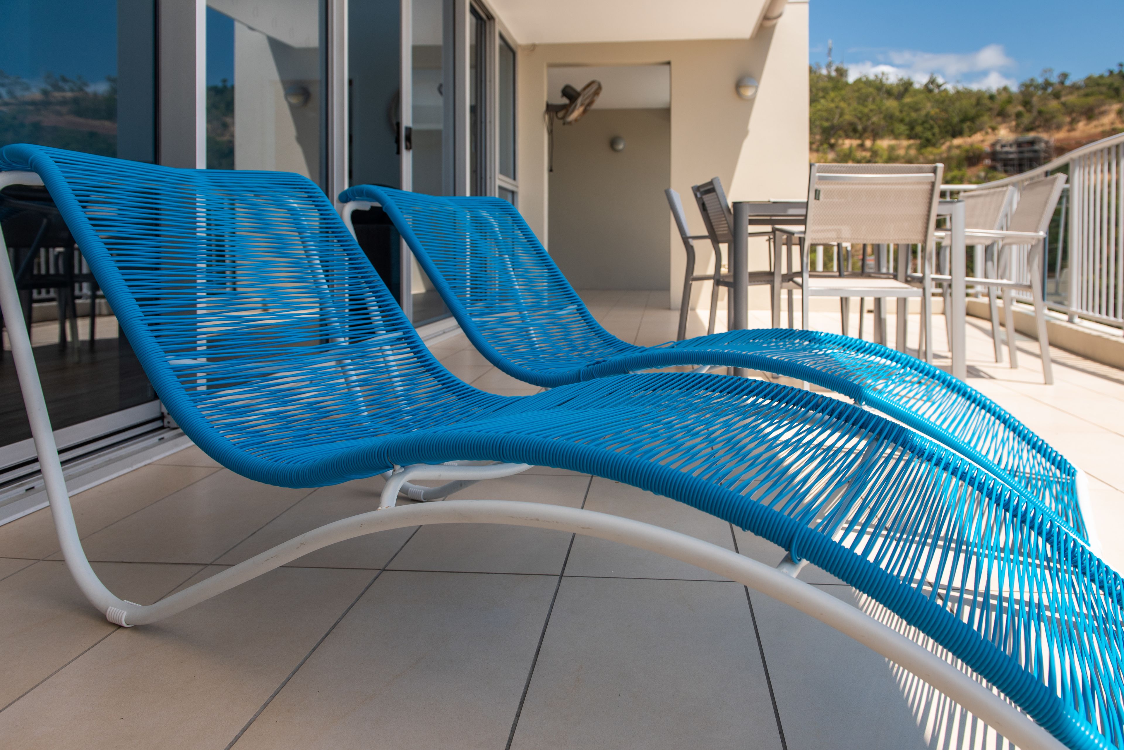Un balcón con dos sillones azules, una mesa y una silla.