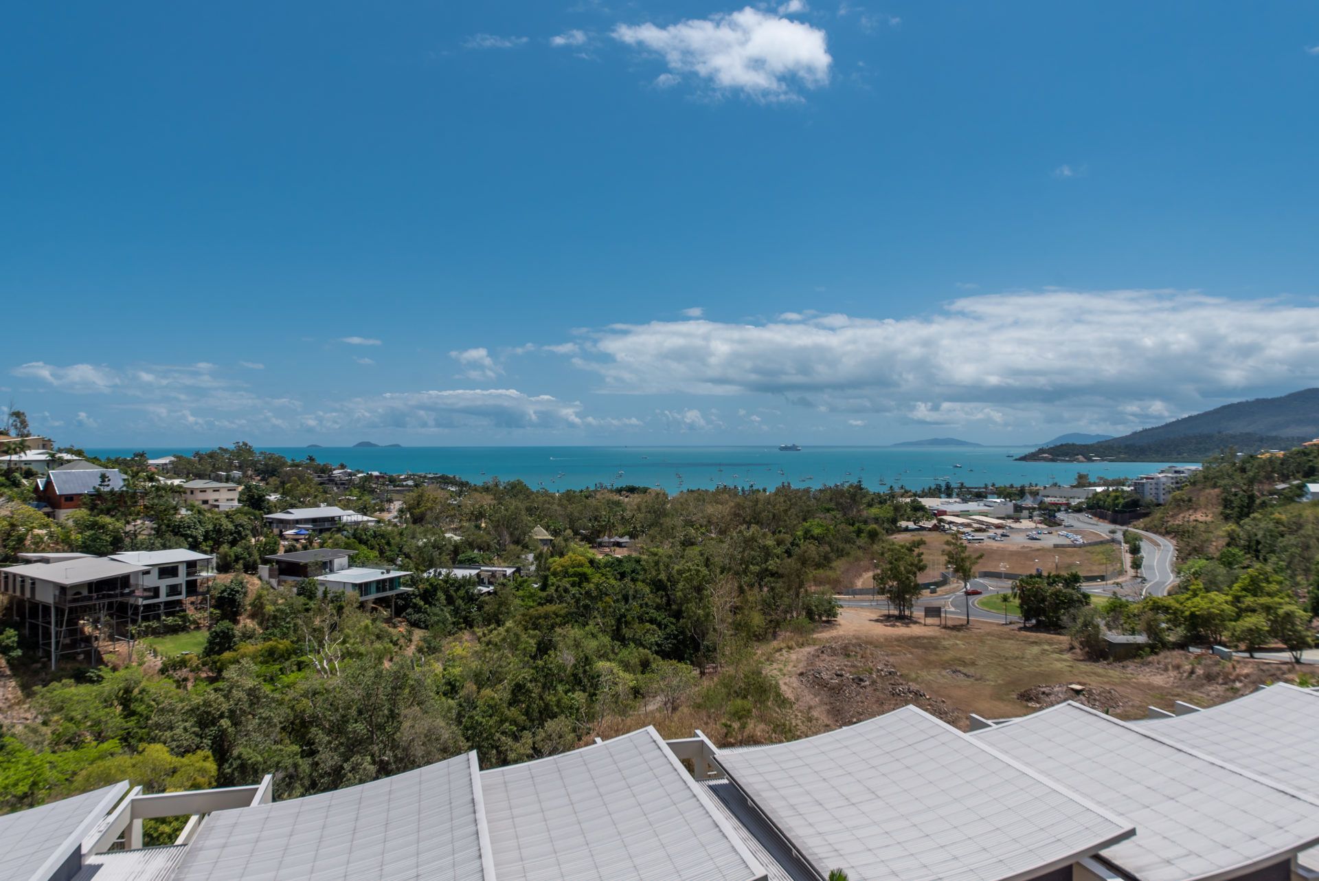 A coastal town with residential buildings, a clear blue sky, and a view of the sea.
