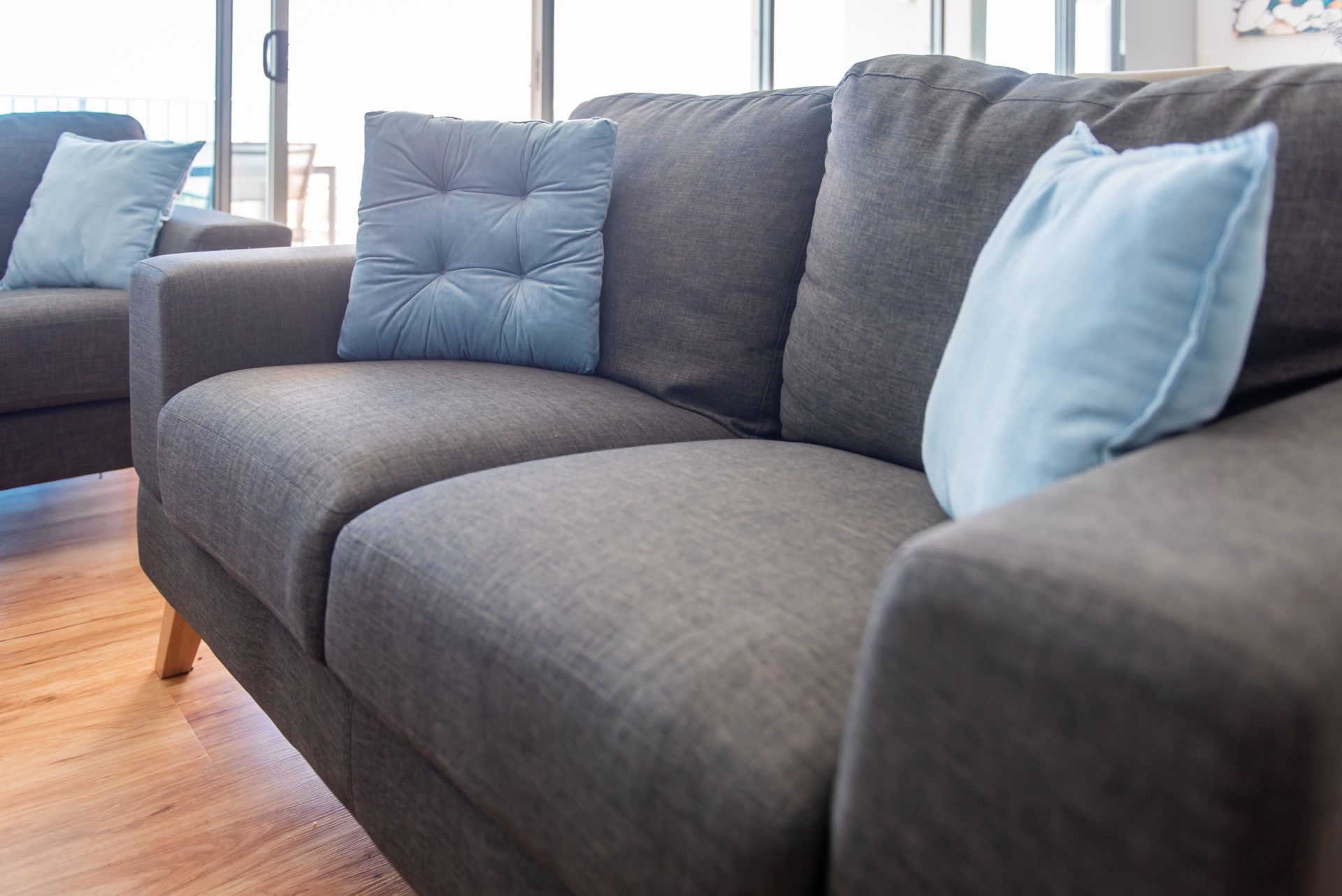 A modern living room with a grey sofa and blue cushions.