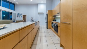 Una cocina moderna con armarios de madera, un refrigerador de acero inoxidable y un horno empotrado.