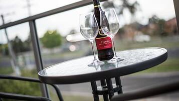 A bottle of Cienna wine on a glass table with a view of a road and greenery in the background.