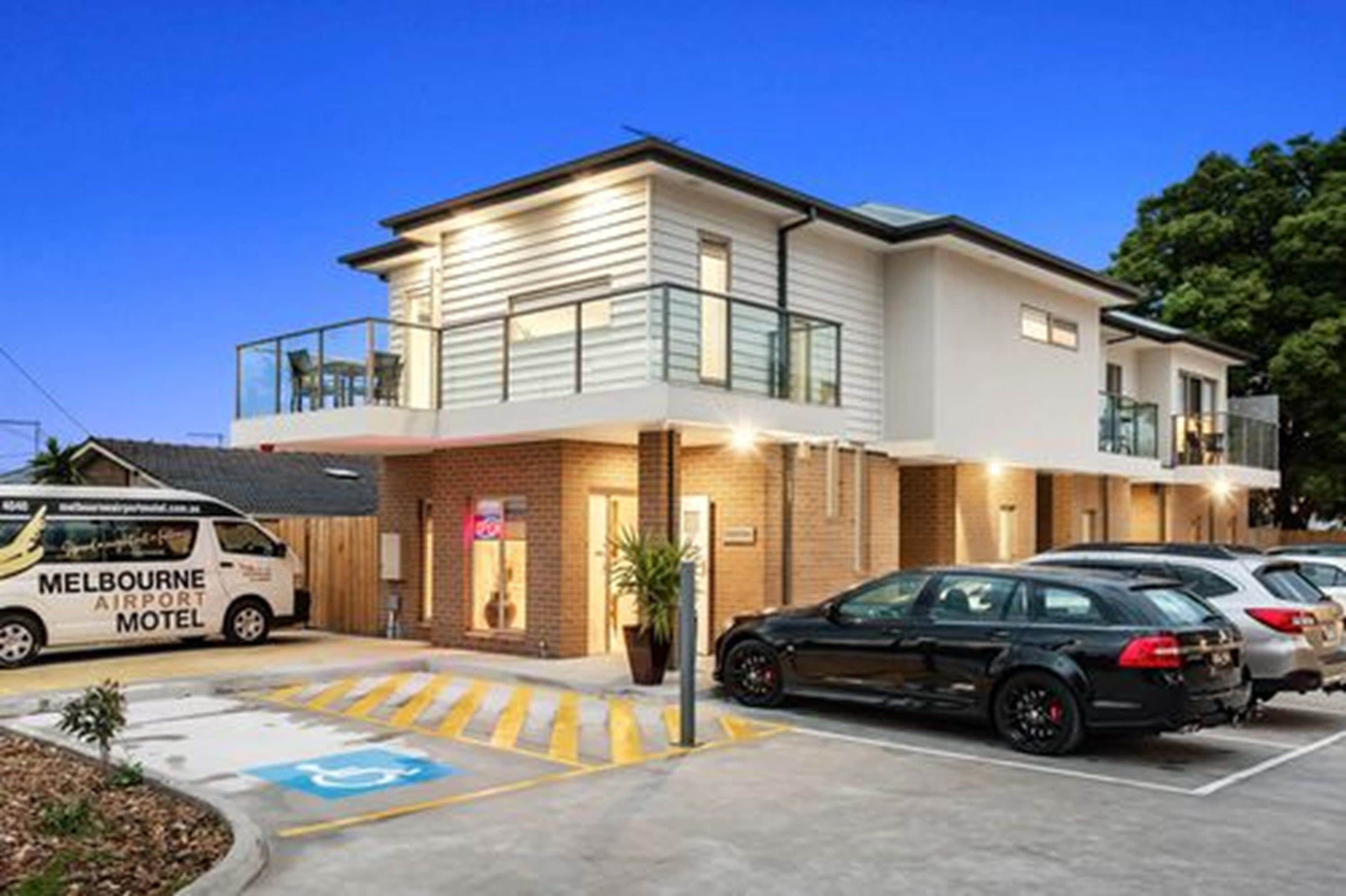 A modern motel with a two-story structure, a covered outdoor area, and a parking lot.
