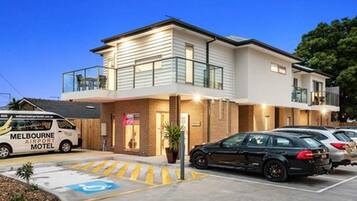 A modern motel with a two-story structure, a covered outdoor area, and a parking lot.