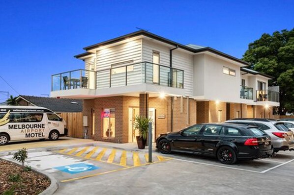 Un motel moderne, composé d’un bâtiment à deux étages, d’un espace extérieur couvert et d’un parking.