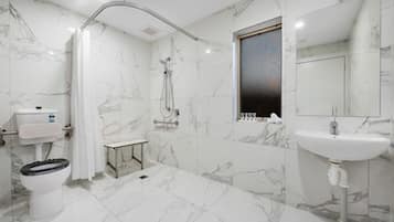 Une salle de bain équipée de toilettes, d’un bidet, d’une douche et d’un lavabo.