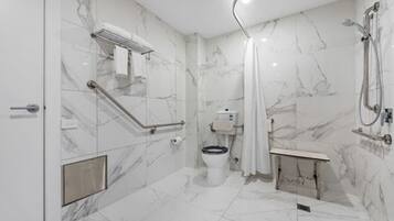 Ein modernes Badezimmer mit Marmorboden, Toilette, Dusche und Haltegriff.