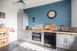 Une cuisine moderne avec un mur d’accent bleu, une horloge et un plan de travail en bois.