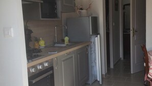 Eine Küche mit grauen Schränken, einem Edelstahlherd und einer Uhr an der Wand.