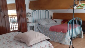 Ein Schlafzimmer mit zwei Betten, Holzboden, einem Metallstockbett und einem Holzschrank.
