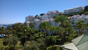 Un quartier résidentiel en bord de mer, avec des bâtiments blancs, des palmiers et une vue dégagée sur la mer.