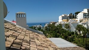 Un quartier résidentiel en bord de mer, avec des bâtiments blancs, un ciel bleu azur et une vue sur la mer.