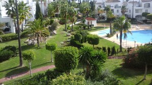 Un complexe hôtelier doté d’une piscine, de palmiers et de bâtiments blancs.