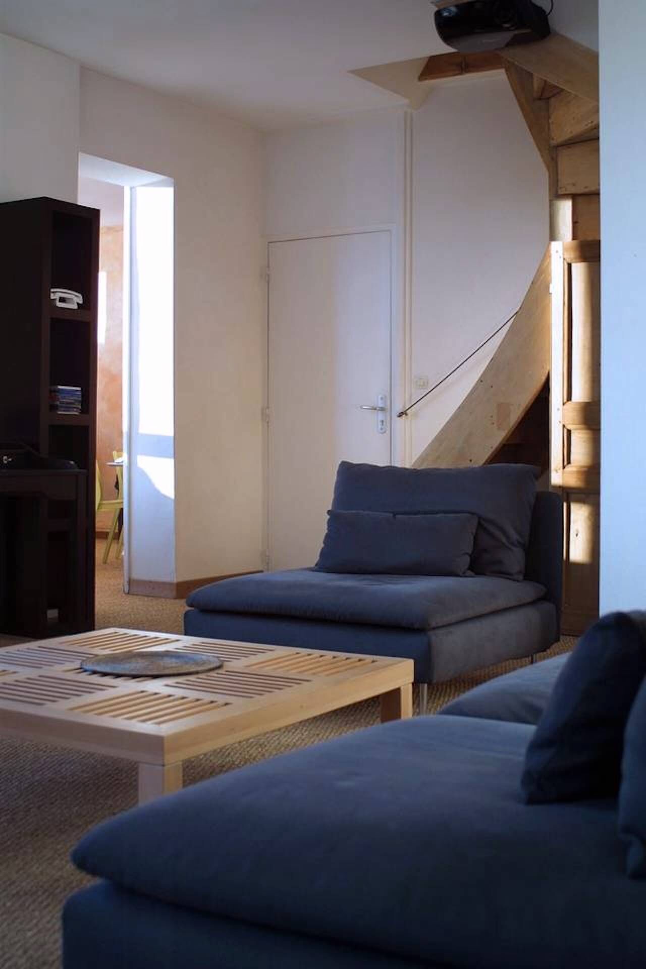 A modern living room with a sofa, a coffee table, and a bookshelf.