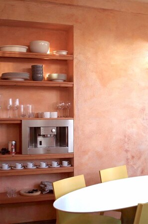 A kitchen with wooden shelves holding plates, bowls, and glasses. There is a microwave and a coffee machine on the counter. - Air conditioned duplex in a 19th century mansion centrally located with parking (Tours)