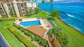 A hotel with a swimming pool, lounge chairs, and a view of the ocean.