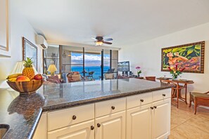 Una cocina con una isla grande, un comedor con vista al océano y un ventilador de techo.
