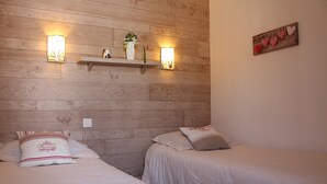 Un dormitorio con dos camas, cabecero de madera, estante empotrado con adornos y apliques de pared.