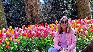 Eine Person sitzt inmitten eines bunten Tulpenfeldes.