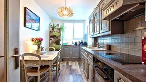 Een keuken met een eettafel, stoelen, kastjes en een hanglamp.