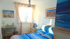 Een slaapkamer met een bed, bureau, stoel en raam met gordijnen.