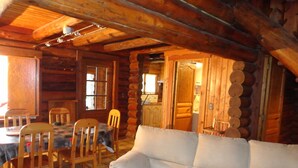 A log cabin interior with a dining area, wooden furniture, and a cozy living space. - The little log with a view of the lake (Marcillac-La-Croisille)