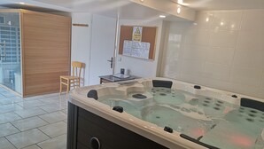 Une salle de bain moderne avec une grande baignoire, une porte en bois, une petite table avec une chaise et un tableau d’affichage contenant des consignes de sécurité.