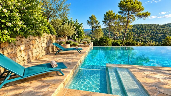 A swimming pool with clear blue water, surrounded by stone walls and green plants.