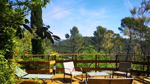 A wooden deck with outdoor furniture, including chairs and a table, surrounded by lush greenery and trees. - L 'OLIVADE LARGE RECENT VILLA WITH PANORAMIC VIEW  (Entrecasteaux)