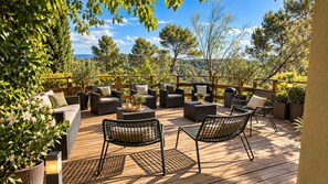 An outdoor patio with wicker furniture, a wooden deck, and potted plants.