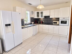 A modern kitchen with white cabinets, a stainless steel refrigerator, a microwave, and a sink.
