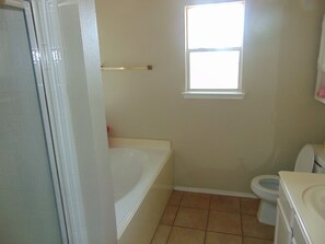 Een bad/douchecombinatie, een haardroger, handdoeken, toiletpapier