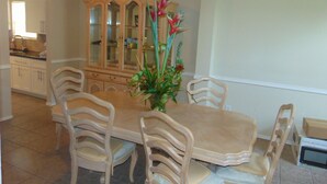 A dining area with a wooden table and matching chairs, a glass-fronted cabinet, and a vase with flowers. - Houston Near Stadium, Galleria and Downtown (Houston)
