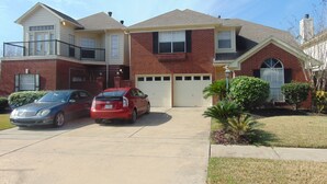 A two-story house with a garage, a driveway, and two cars parked in the driveway. - Houston Near Stadium, Galleria and Downtown (Houston)