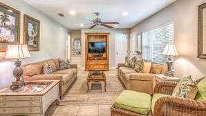 A living room with two sofas, a coffee table, a TV stand, and a ceiling fan.