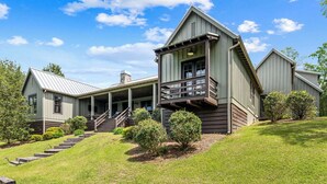 A large, modern house with a prominent front porch, a staircase leading to the entrance, and a well-maintained lawn. - Modern Lake House on Smith Lake, AL close to Birmingham and Huntsville (Bremen)